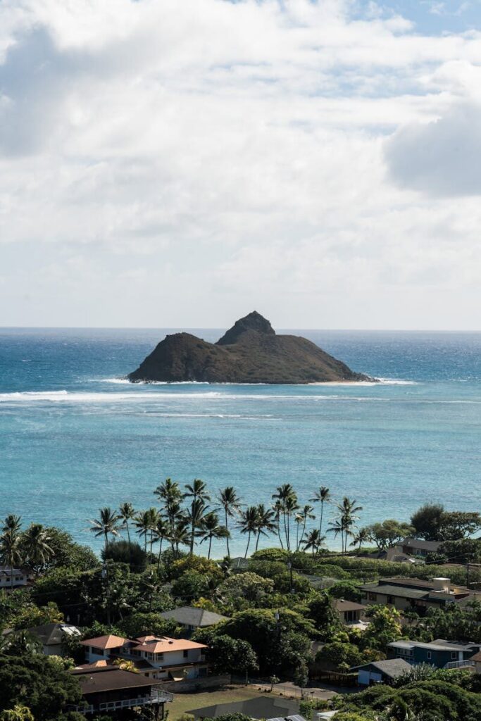 Stunning aerial view of the Na Mokulua twin islands off Lanikai Beach, lush greenery and palm trees in foreground.