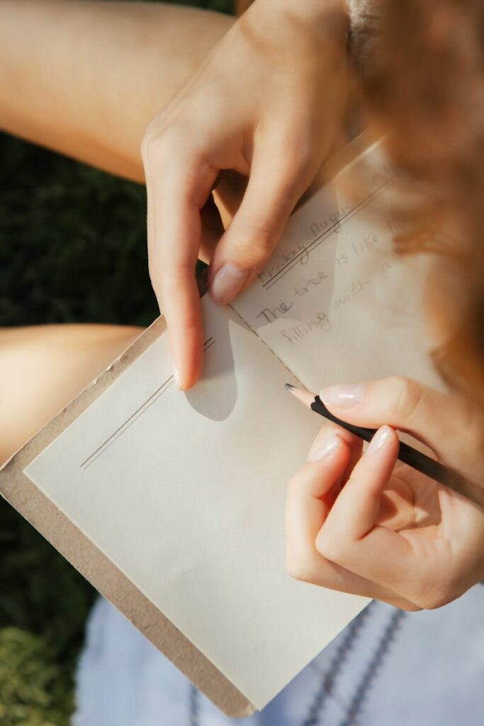 Close-up of a woman writing in a notebook outdoors in natural light.