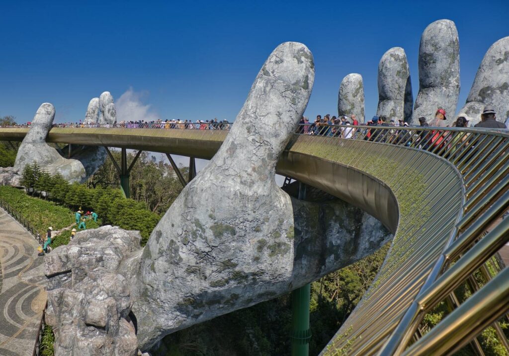The iconic Golden Bridge with giant hand sculptures at Ba Na Hills, Vietnam, under a clear blue sky.