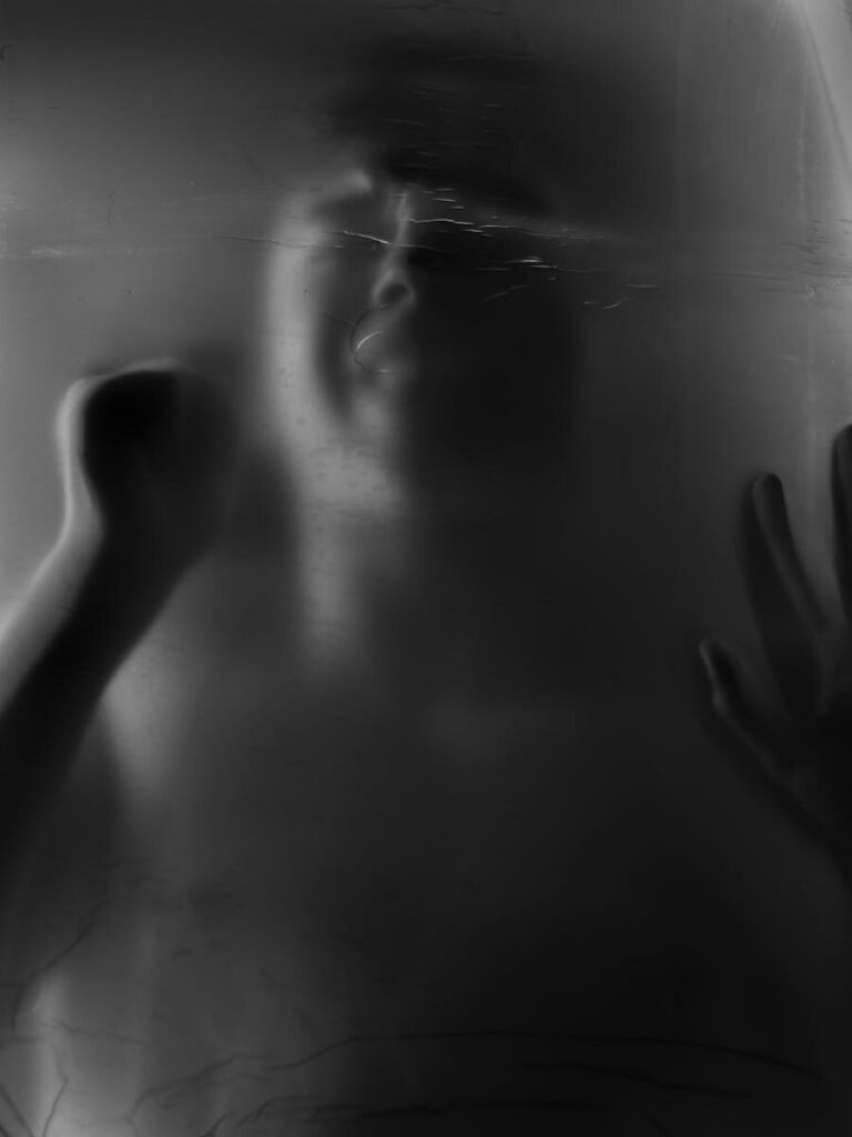 Artistic silhouette of a person behind foggy glass, conveying mystery and emotions.
