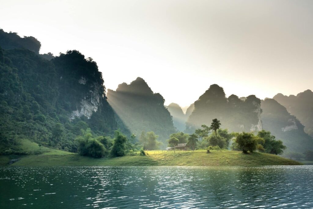 Peaceful scene of sunlit mountains and a tranquil lake in Tuyen Quang, Vietnam.